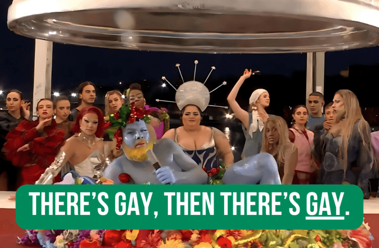 A diverse group of performers in colorful, avant-garde costumes at a vibrant event with the text "THERE'S GAY, THEN THERE'S GAY."